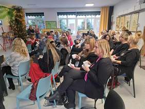 Uczestnicy spotkania siedzą na krzesłach na sali