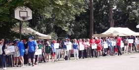 Pokaż zdjęcie: Stojąca grupa zawodników z tabliczkami, na których znajdują się nazwy placówek