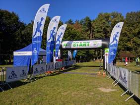 Pokaż zdjęcie: Dmuchana brama z napisem Start, wokół flagi sponsora biegu