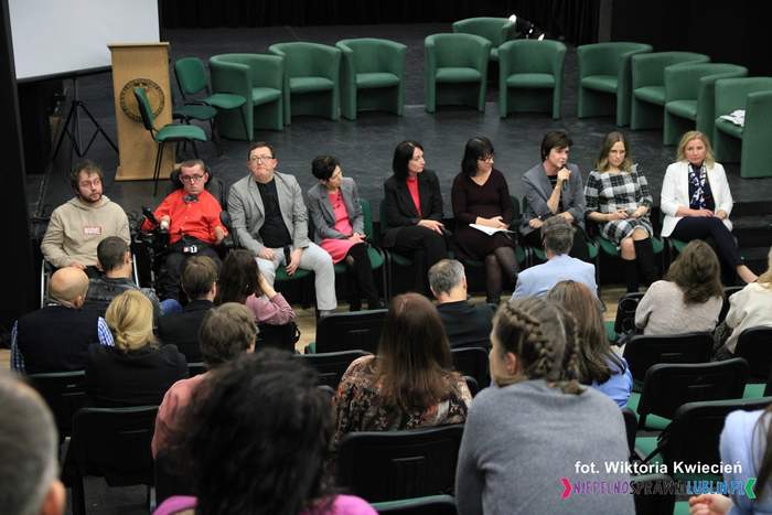Pokaż zdjęcie: Zdjęcie dziewięciu panelistów biorących udział w dyskusji, trzech mężczyzn i sześć kobiet. Zdjęcie robione z audytorium w kierunku sceny.