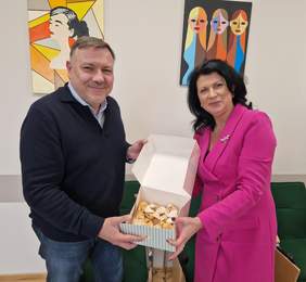 Pokaż zdjęcie: Uśmiechnięci mężczyzna i kobieta trzymają pudełko, w którym jest chrust.