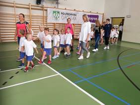 Pokaż zdjęcie: Na salę wchodzą uczestnicy X Integracyjnego Turnieju Gier i Zabaw dla najmłodszych „Szybciej, razem, dalej”