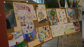 Pokaż zdjęcie: Na dwóch sztalugach wiszą tablice, na których znajdują się prace plastyczne wykonane przez dzieci. 