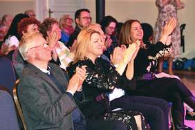 Pokaż zdjęcie: Widoczni goście w rzędach oglądający artystów na scenie.