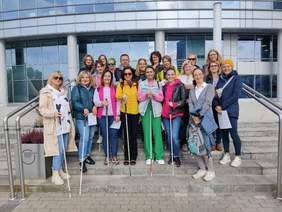 Pokaż zdjęcie: Grupa ludzi pozujących do zdjęcia na schodach. Część z nich ma laski dla niewidomych