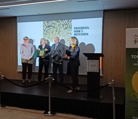 Pokaż zdjęcie: Na scenie stoją cztery osoby, trzy kobiety oraz mężczyzna. Prezentują wręczony grawerton.