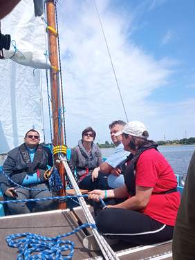 Pokaż zdjęcie: Zdjęcie czterech osób siedzących w żaglówce.