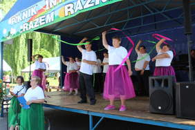 Pokaż zdjęcie: Na scenie występy artystyczne uczestników warsztatów, tańczą i machają pałeczkami z kolorowymi taśmami