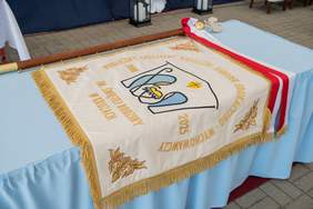 Pokaż zdjęcie: Sztandar leżący na stole przykrytym białym obrusem