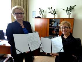 Pokaż zdjęcie: Dwie kobiety stoją trzymając w rękach podpisane dokumenty