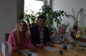 Pokaż zdjęcie: Przy stole mężczyzna i dwie kobiety podpisują dokumenty.