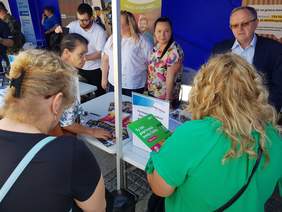 Pokaż zdjęcie: Dyrektor Oddziału Świętokrzyskiego  udziela informacji na stoisku na Targach Pracy