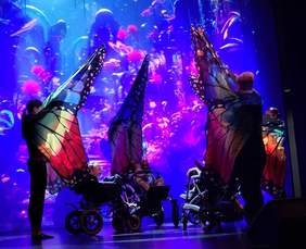Pokaż zdjęcie: Na scenie występy artystyczne. Taneczny pokaz motyli z osobami na wózkach 