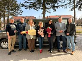 Grupa osób stoi na tle nowego auta dofinansowanego z PFRON