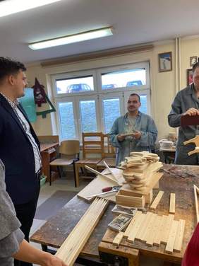 Pokaż zdjęcie: Dyrektor PFRON obserwował, jak uczestnicy warsztatów pracują z narzędziami stolarskimi i wycinają ze sklejki renifery, choinki i inne świąteczne ozdoby