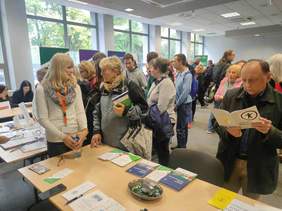 Pokaż zdjęcie: tłum osób na Targach Pracy. Część osób podchodzi do stoisk i rozmawia m.in. z przedstawicielami PFRON