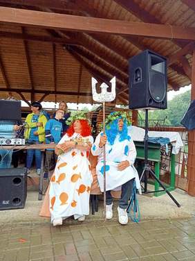 na scenie siedzi królowa i król mórz, sprzęt nagłaśniający, z tyłu sylwetki 3 osób