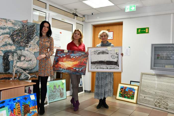 Pokaż zdjęcie: Na korytarzu stoją trzy panie, członkinie komisji konkursowej. W rękach, każda z Pań trzyma oceniane prace.