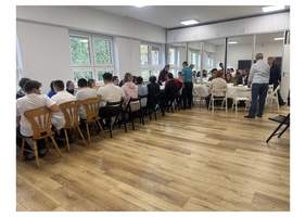 Pokaż zdjęcie: Uczestnicy warsztatów i pracownicy Fundacji Teatroterapia Lubelska podczas wspólnego spotkania przy stołach w sali zajęciowej.