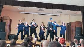 Pokaż zdjęcie: Scena na której tańczy grupa osób.