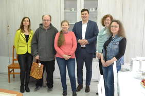 Pokaż zdjęcie: Na zdjęciu widnieją cztery kobiety i dwóch mężczyzn. Młody mężczyzna trzyma torbę z nagrodą. Stoją na tle szafy