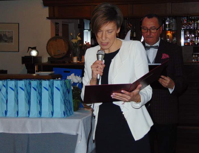 Pokaż zdjęcie: Kobieta stojąca z mikrofonem, czytająca list