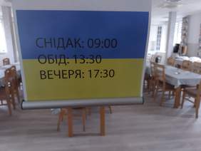 tablica w kolorach flagi ukraińskiej, na niej napisy dotyczące godzin posiłków