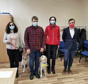 Pokaż zdjęcie: SToją obok siebie kobieta z psem, mężczyzna z psem, kobieta w czerwonym polarze, mężczyzna w marynarce 