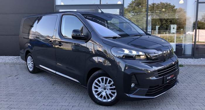 Pokaż zdjęcie: Nowoczesny mikrobus w kolorze czarnym prezentowany przy salonie samochodowym