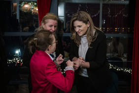 Pokaż zdjęcie: Trzy kobiety składają sobie życzenia, w rękach trzymają opłatek.