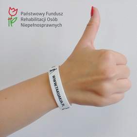 Pokaż zdjęcie: Dłoń z wyciągniętym kciukiem na tle ściany. Powyżej logo PFRON.