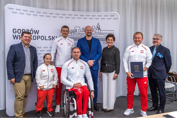 Pokaż zdjęcie: Zdobywcy medali Igrzysk Paraolimpijskich z Gorzowa Wielkopolskiego wraz z trenerem i władzami Gorzowa Wielkopolskiego na tle ścianki promocyjnej Urzędu Miasta Gorzowa Wielkopolskiego