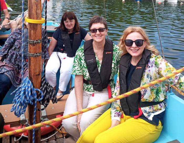Pokaż zdjęcie: Zdjęcie trzech roześmianych kobiet podczas rejsu żaglówką.