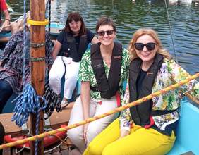 Pokaż zdjęcie: Zdjęcie trzech roześmianych kobiet podczas rejsu żaglówką.