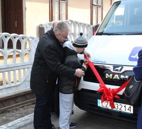 Pokaż zdjęcie: Jerzy Dębski Dyrektor Oddziału Lubelskiego PFRON pomaga wychowankowi PSONI w przecięciu wstęgi na nowym busie