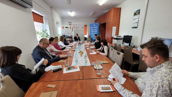 Pokaż zdjęcie: Przy stole konferencyjnym siedzi grupa osób.