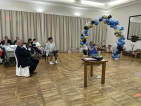 Uczestnicy uroczystości na sali balowej podczas prezentacji multimedialnej