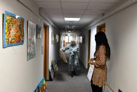 Korytarz, pod ścianami ustawione prace plastyczne. Na pierwszym planie Pani Dorota Jankowska trzymająca notatki, w głębi stoi Pani Katarzyna Haber trzymająca w ręku jedną z ocenianych prac.