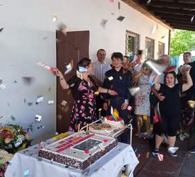 Pokaż zdjęcie: 25-lecie WTZ przy Dywizjonu 303 w Krakowie, grupa radosnych uczestników, tort i konfetti