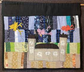 Pokaż zdjęcie: Praca wykonana z wyszywanych materiałów. Obrazuje budynek i przelatujące nad nim trzy ptaki w kolorze żółtym różowym i czerwonym. Tło wykonane z kolorowych wzorzystych materiałów. Góra w odcieniach niebieskiego, dół w odcieniach zieleni.