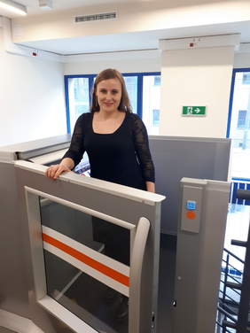 Pokaż zdjęcie: Pracownik bhp demonstruje zalety nowoczesnego podnośnika  kabinowego dla osób z niepełnosprawnością ruchową