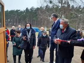 Pokaż zdjęcie: Zaproszeni na uroczystość goście symbolicznie przecinają wstęgę, otwierając warsztat terapii zajęciowej 