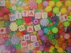 Pokaż zdjęcie: kolorowy napis witamy was na wtz utworzony z koralików wokół porozrzucane kolorowe koraliki z otworami w różnych kształtach