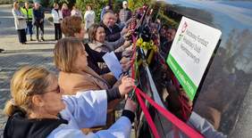 Pokaż zdjęcie: Kilka osób przecina wstęgę przyczepioną do samochodu.