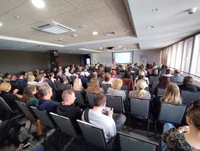 Pokaż zdjęcie: Zdjęcie sali konferencyjnej zrobione z tyłu, w kierunku prelegenta.