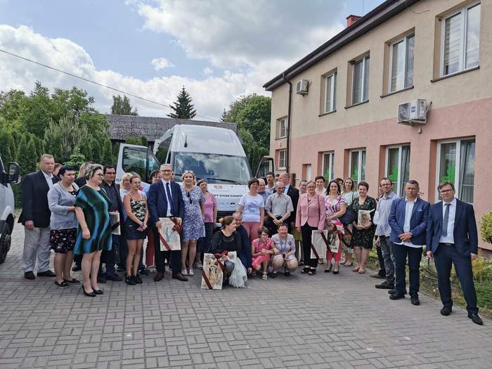 Pokaż zdjęcie: Przy białym aucie marki Iveco stoi duża grupa osób i pozuje do pamiątkowego zdjęcia