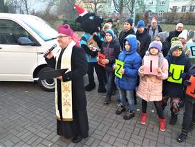 ksiądz i dzieci stoją przed samochodem
