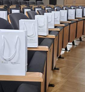 Torebki reklamowe z materiałami czekają na gości, ułożone na podłokietnikach siedzeń