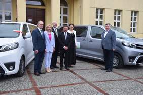 Pokaż zdjęcie: Przy busie pozuje do pamiątkowego zdjęcia sześć osób. Dwie kobiety i czterech mężczyzn. Osoby te stoją przy nowych busach.