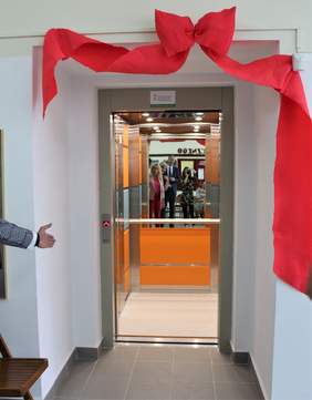 Pokaż zdjęcie: Otwarta winda gotowa do pierwszego kursu - w środku lustro i pomarańczowe ściany